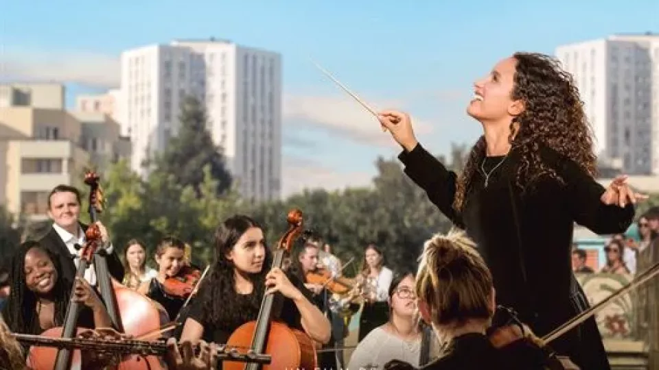 Bildbeschreibung: Filmplakat von Divertimento. Eine Frau dirigiert ein Orchester im Freien. Im Hintergrund sind hohe Gebäude und ein paar Bäume zu sehen.